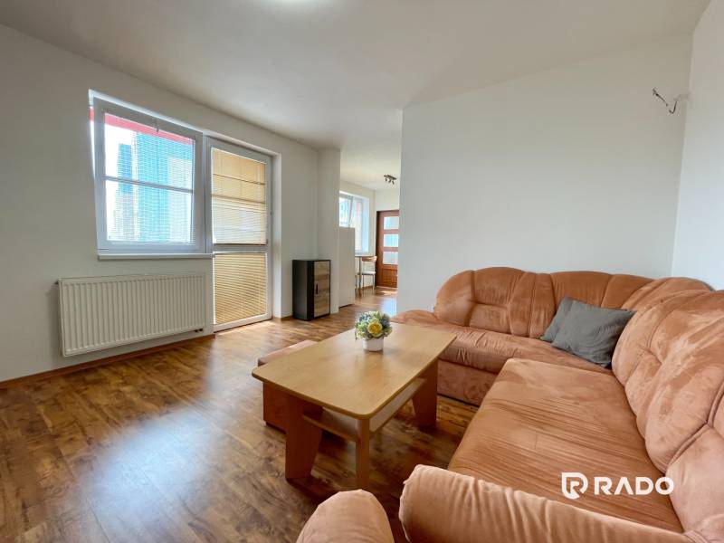 Living room in a two-room apartment with an orange sofa and a wooden table.