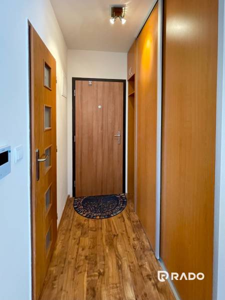 A hallway in a 2-room apartment with a wooden floor and a built-in wardrobe.