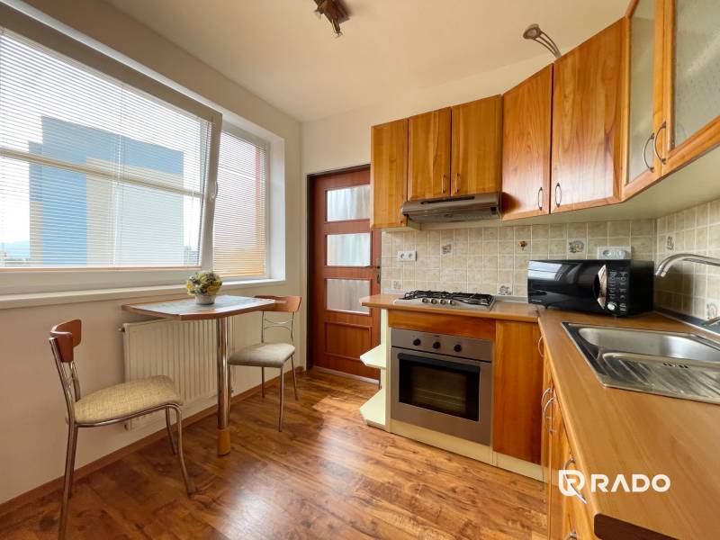 A kitchen in a 2-room apartment with a wooden cabinet and a table by the window.