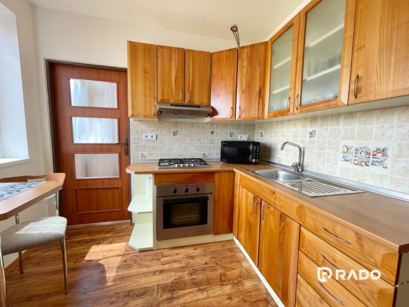 A kitchen in a 2-room apartment with wooden cabinets and appliances.