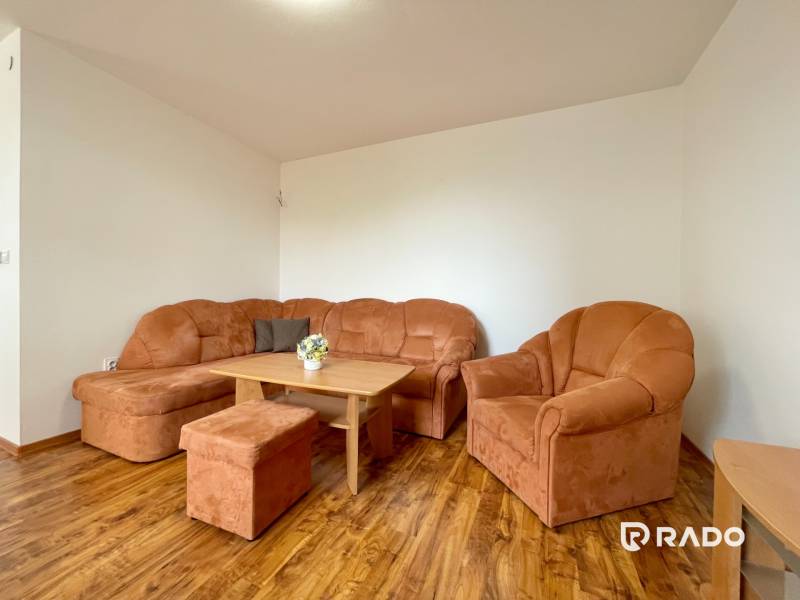 Living room with an orange sofa in a two-room apartment with wooden flooring.