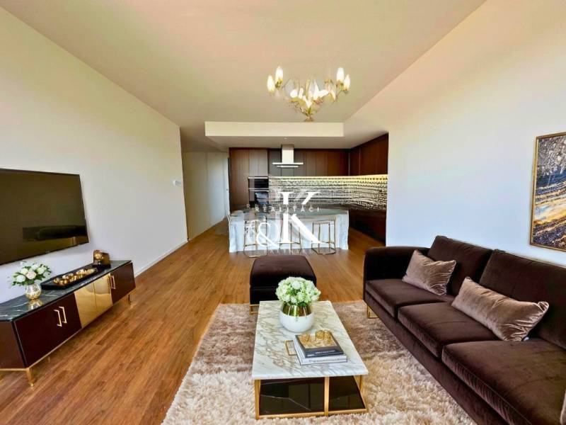 Living room in a two-room apartment with a sofa, TV, and dining area.