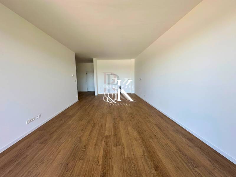 Spacious room in a 2-room apartment with wooden flooring and white walls.