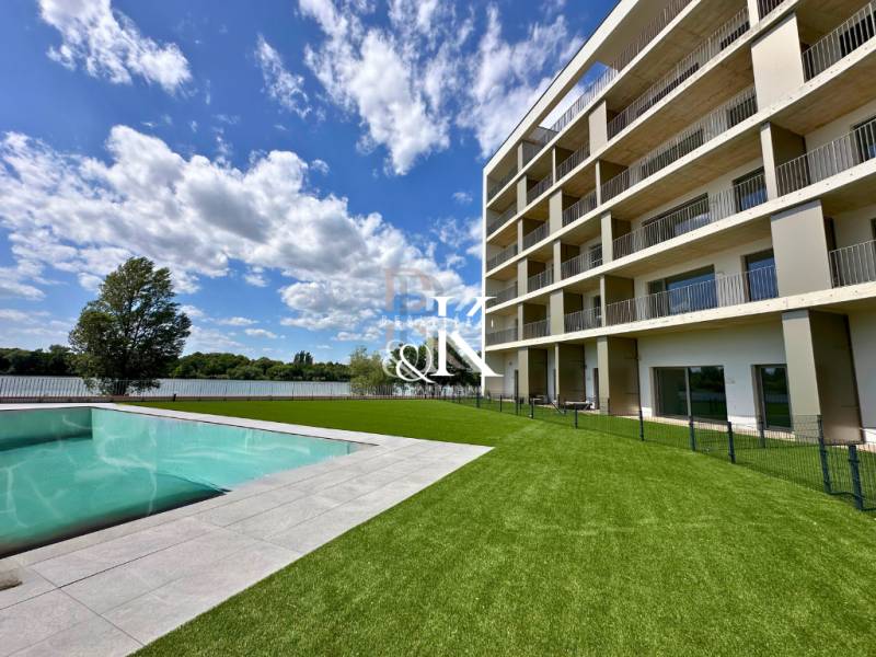 A building with a pool and landscaped lawn by the water in Banka, an ideal location.