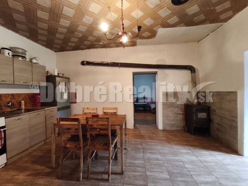 A kitchen in a family house with a wooden ceiling, a table, and a stove.