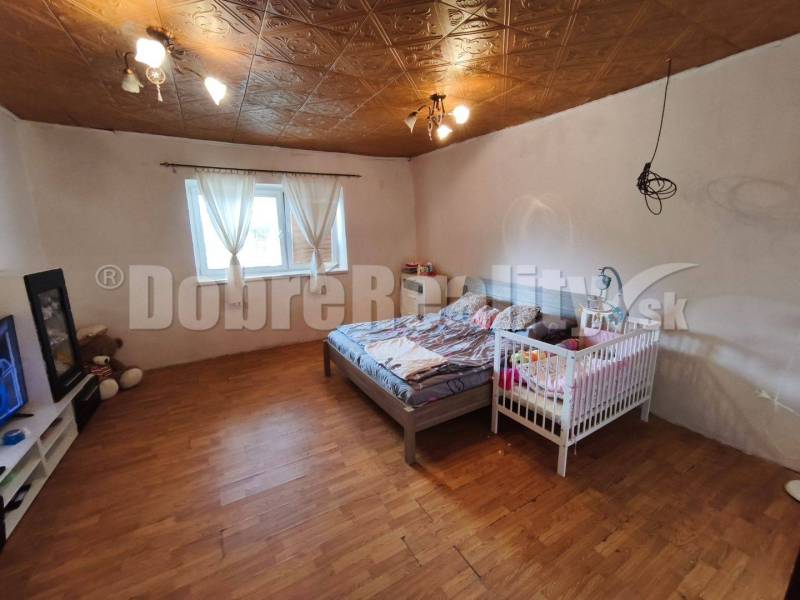 Bedroom in a family house with a bed, a crib, and wooden flooring.