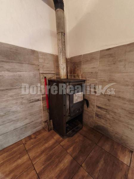 A fireplace in the corner of a family house room with wooden paneling and tiles.