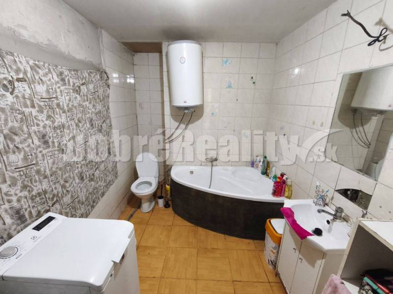 Bathroom with a bathtub, washing machine, toilet, and boiler in a family house.