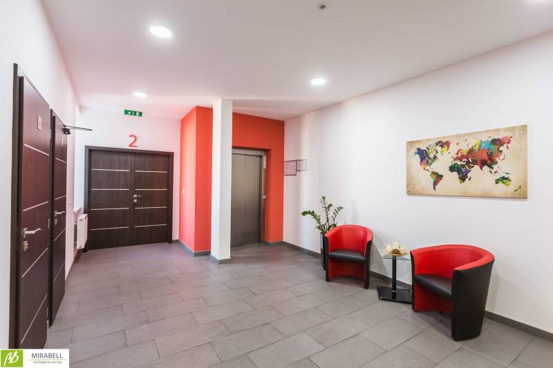 A hall with two red armchairs, a world map, and an elevator in the offices.