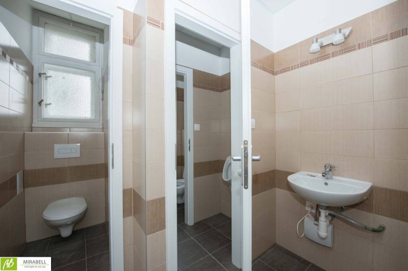 Bathroom in offices with beige tiles and a sink.