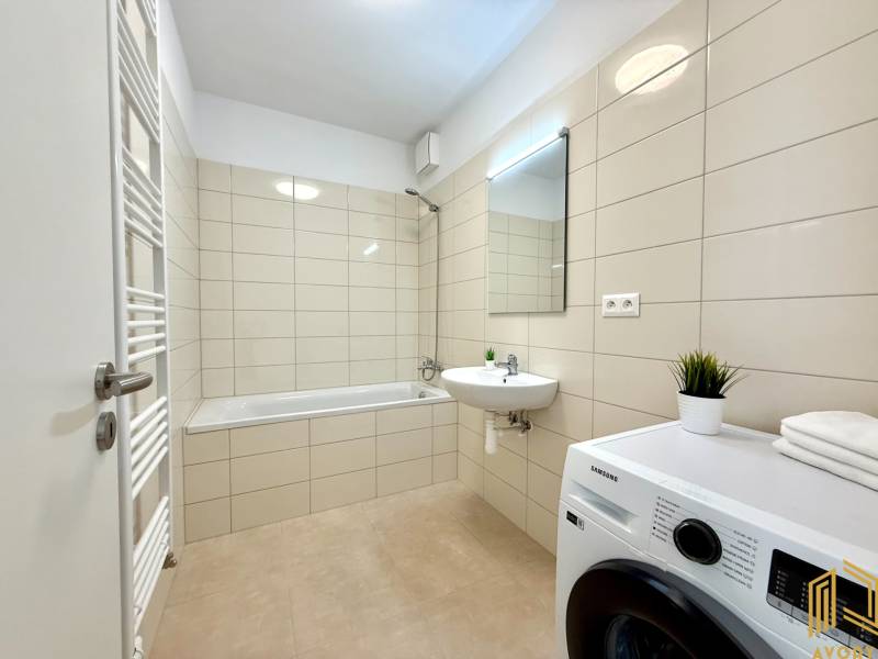 Bathroom with a bathtub, sink, washing machine, and radiator in a 2-room apartment.