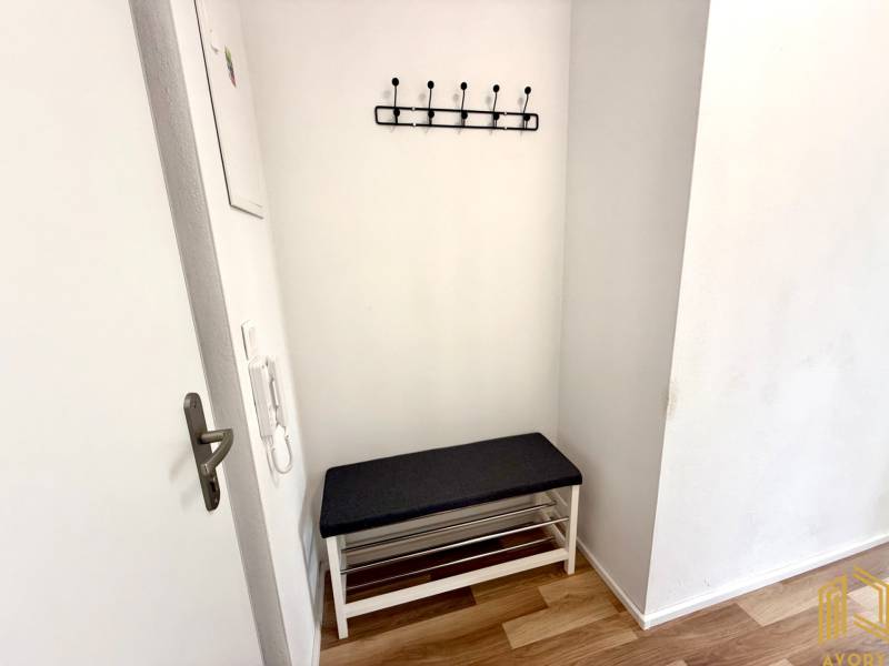 Entrance hallway in a 2-room apartment with a bench and a wall-mounted coat rack.