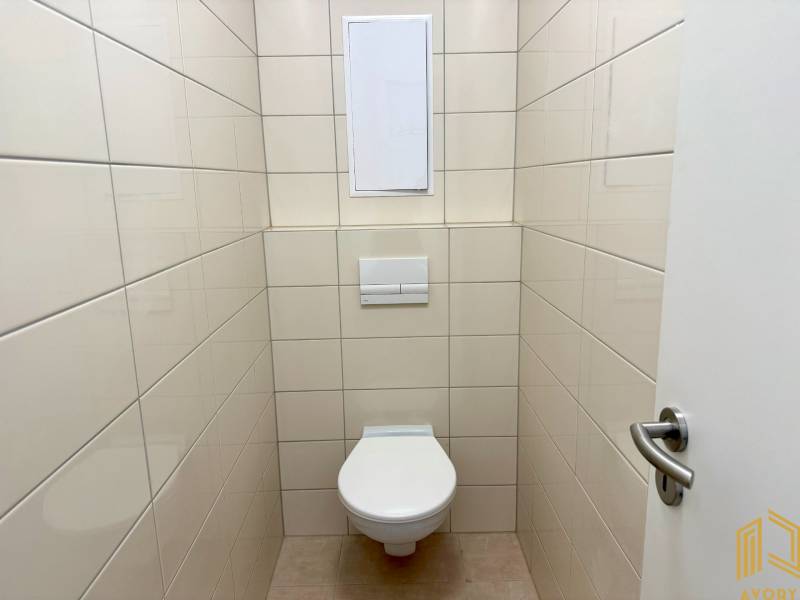 A toilet with tiles in a 2-room apartment, light-colored tiles.