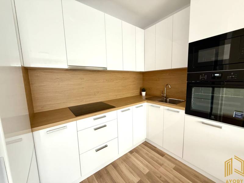 A kitchen in a 2-room apartment with white cabinets and a wooden countertop.