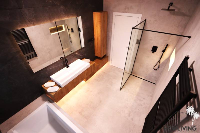 A bathroom with wooden furniture, a shower enclosure, and a dark wall in a family house.