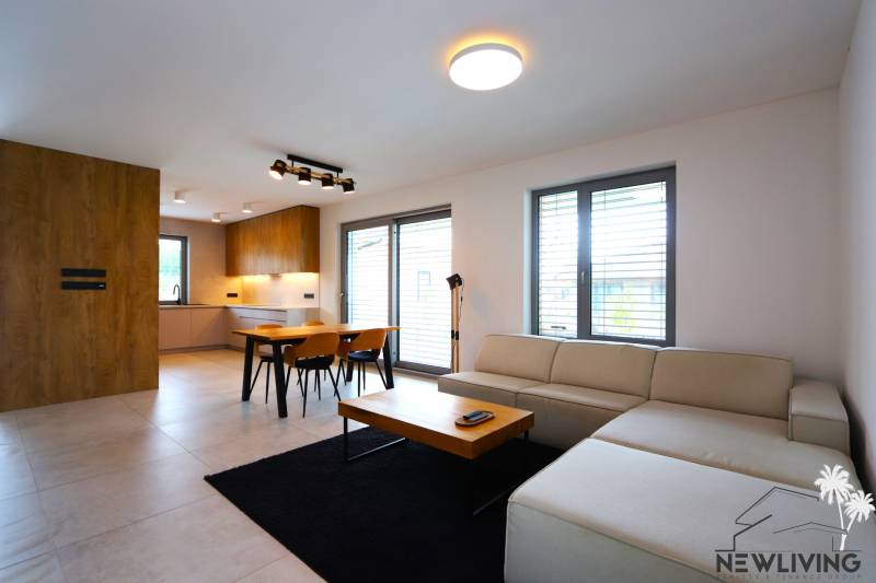 Living room with kitchen, dining table, sofa, and wooden elements in a family house.