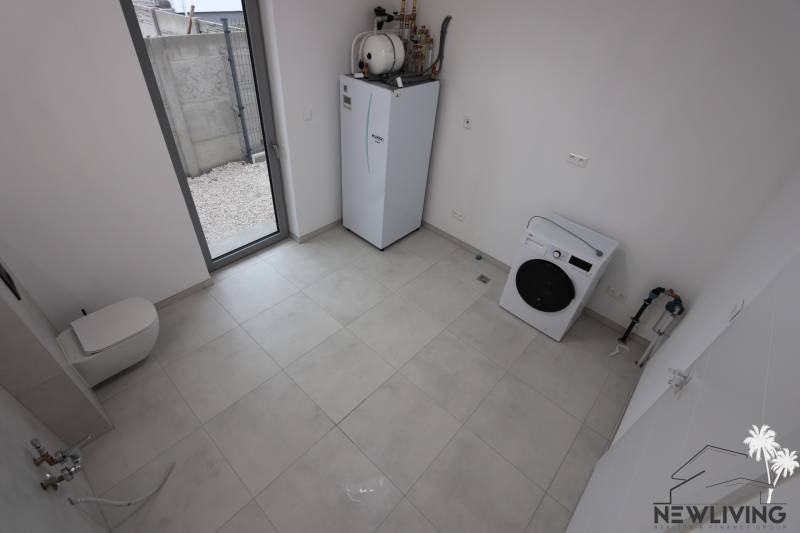 Laundry room in a family house with appliances and a large window.