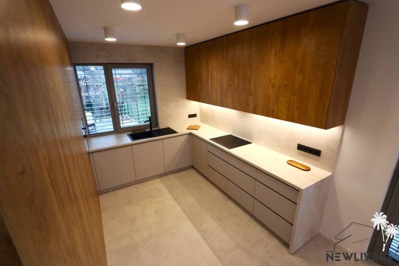 A kitchen with a wooden cabinet, a window, and gray cabinets in a family house.