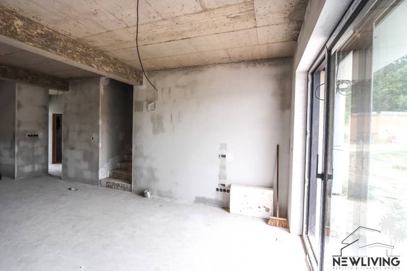 The interior of an unfinished family house, concrete walls and stairs lead to the upper floor.