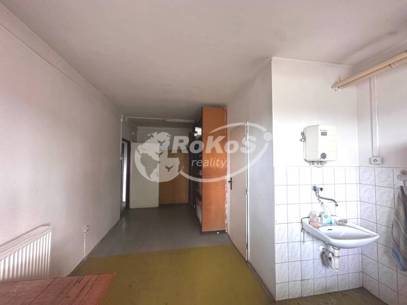 A sink and storage space in commercial premises with a hot water radiator.