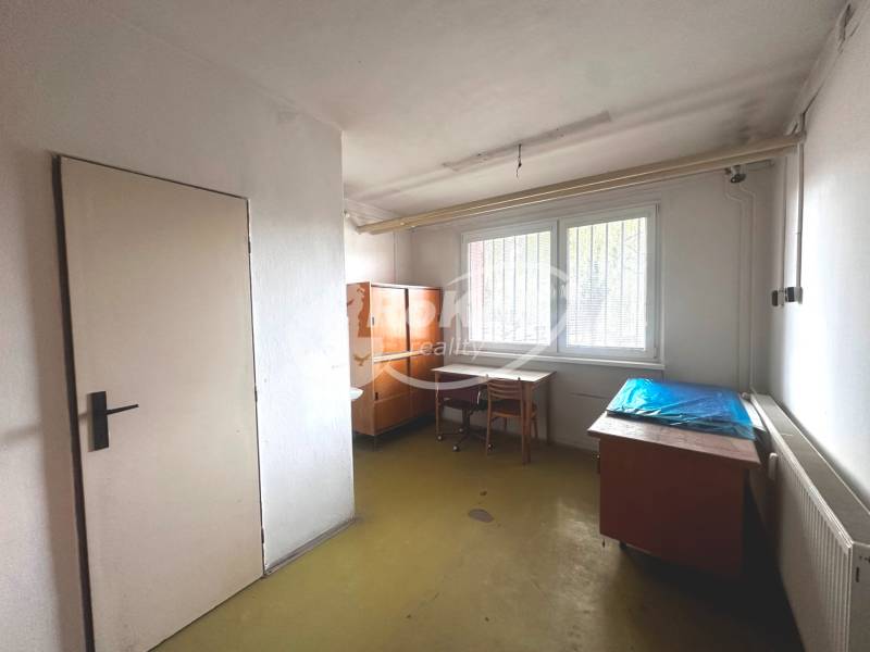 An office in commercial premises contains desks, chairs, cabinets, and a radiator.