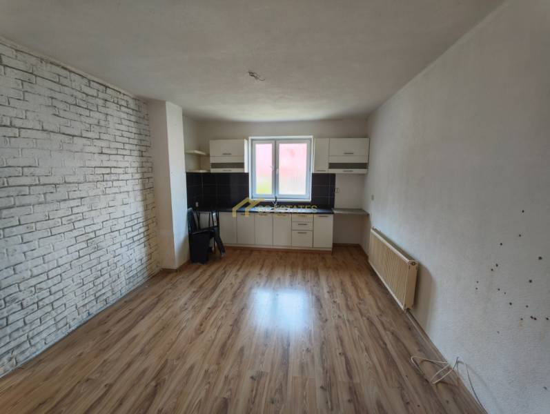 Interior of a family house with a kitchen unit, laminate flooring, and a brick wall.