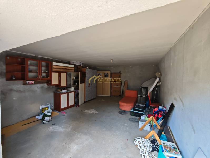 The interior of a garage in a family house with shelves, cabinets, and various stored equipment.