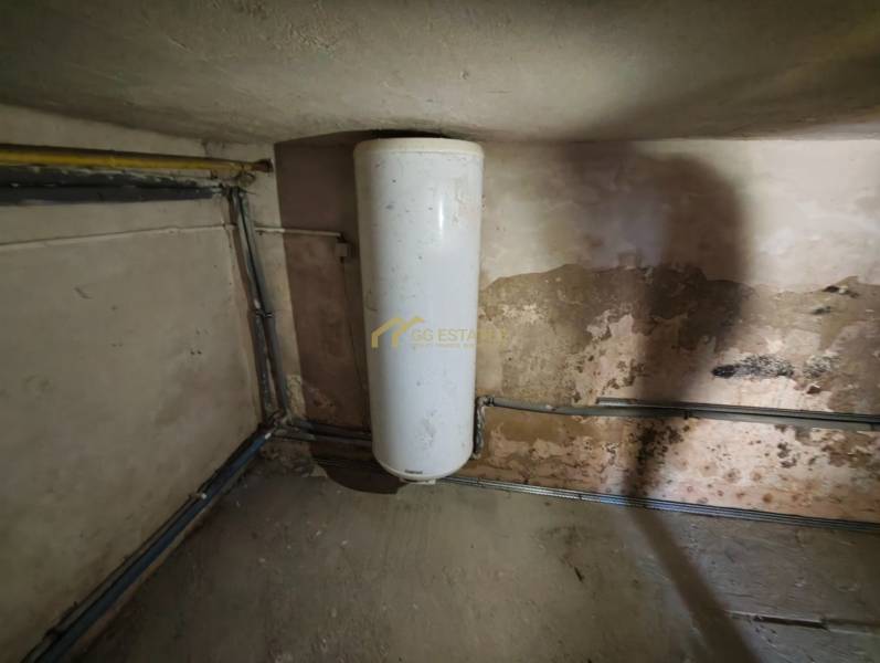 Water tank in a family house with a worn wall and piping.