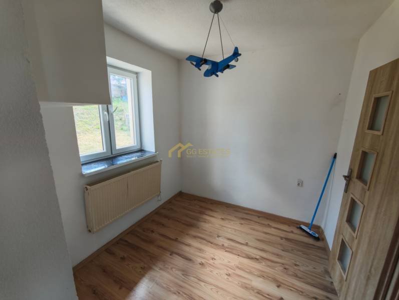A room with a blue airplane-shaped chandelier, wooden floor, and a window, in a family house.