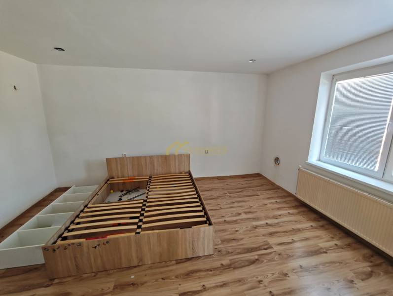 Bedroom with a bed and laminate flooring in a family house.