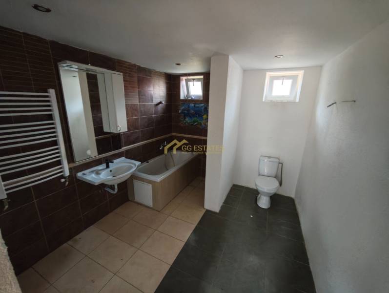 A bathroom in a family house with a bathtub, toilet, and sink, brown tiles.