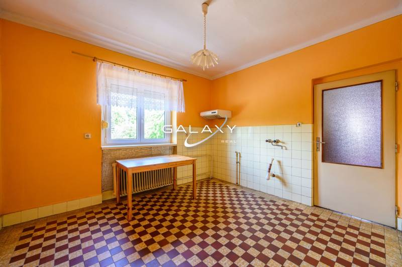 A kitchen with orange walls and a checkered floor in a family house.
