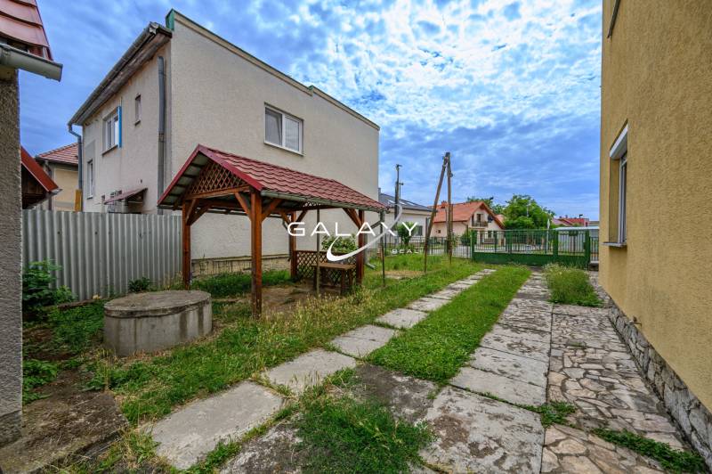 A family house in Vidiná with a carport and a well in a landscaped garden.