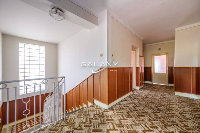 A hallway in a family house with wooden paneling and a patterned carpet.