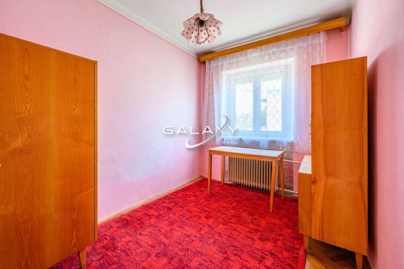 A room in a family house with pink walls, furniture, and a red carpet.