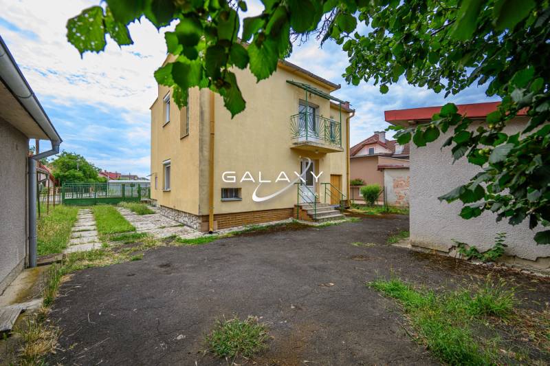 A family house in Vidiná with a garden, lawn, and surrounding buildings.
