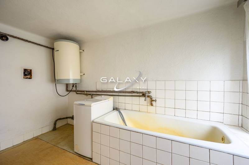 Bathroom in a family house with a bathtub, boiler, and washing machine.