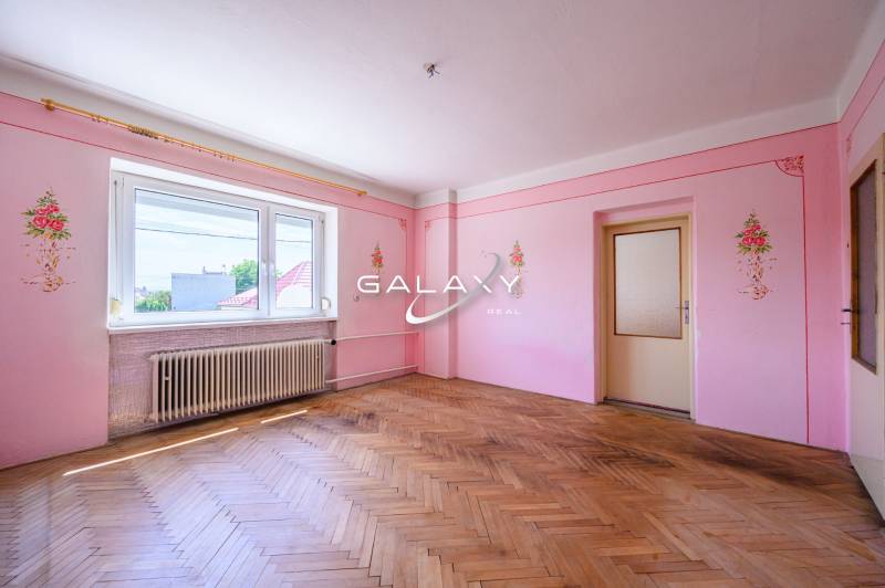 Pink walls with floral decorations, wooden floor, large window in a family house.