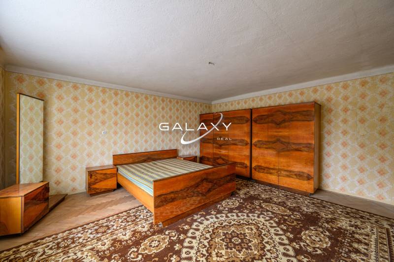 Bedroom in a family house with wooden furniture and retro patterns on the walls.