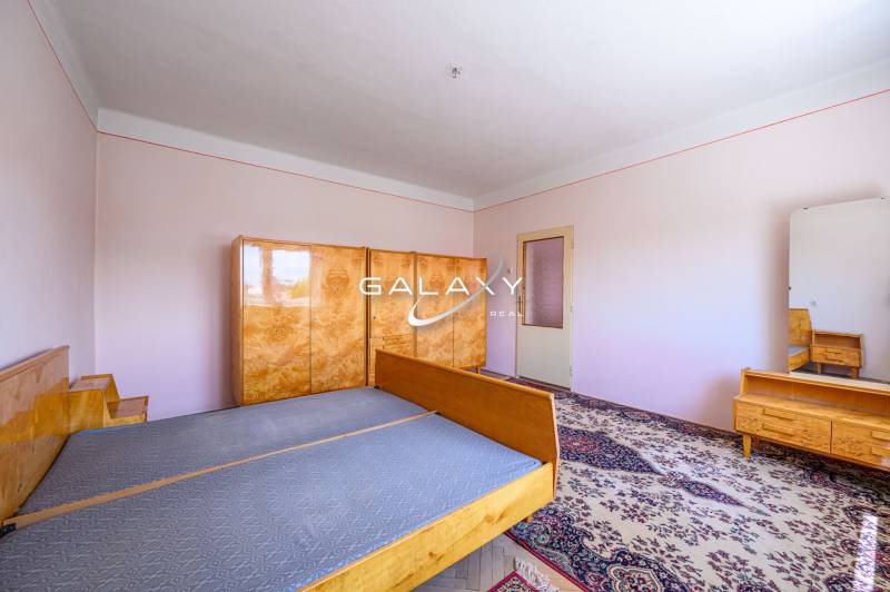 A bedroom in a family house with wooden furniture and a carpet on the floor.