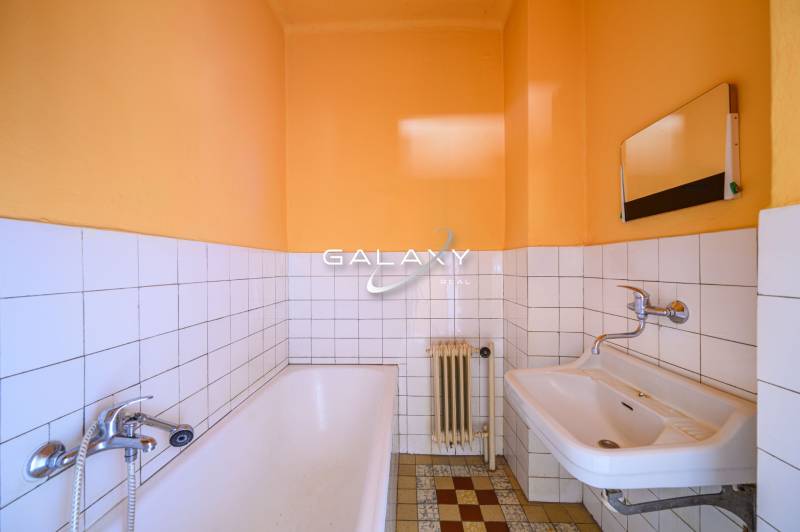A bathroom in a family house with a bathtub, a sink, and tiles on the wall.