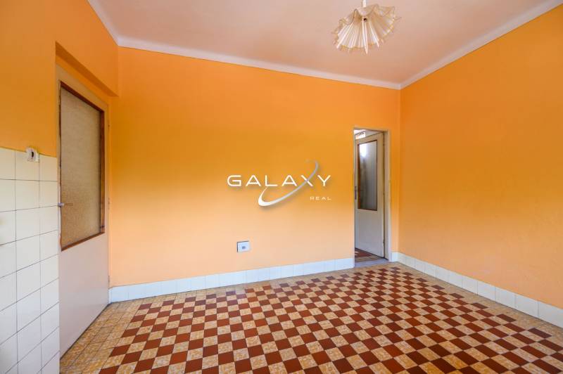 A room in a family house with orange walls and a tiled pattern on the floor.