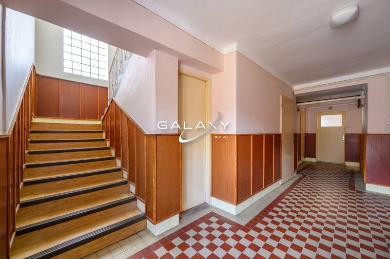 A hallway in a family house with wooden stairs and tiles combined with a wall.