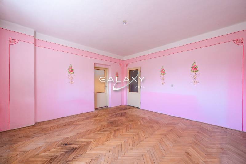 Pink interior of a family house with wooden flooring and floral patterns on the walls.
