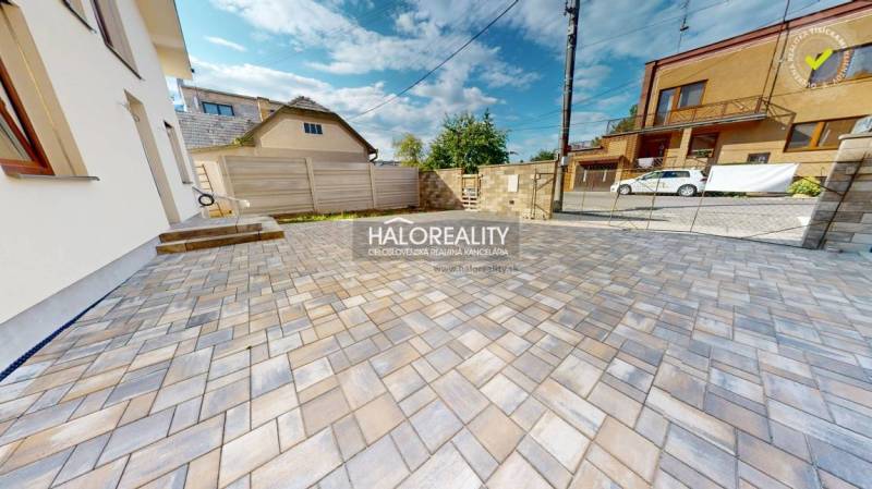 A paved courtyard at a family house in Rimavská Sobota with a fence and parking spaces.
