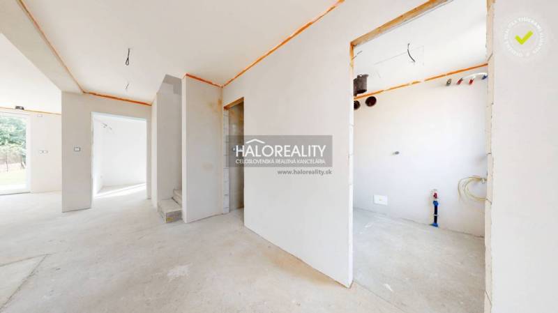 An empty interior in a family house, ready for completion, with a view of the outside yard.