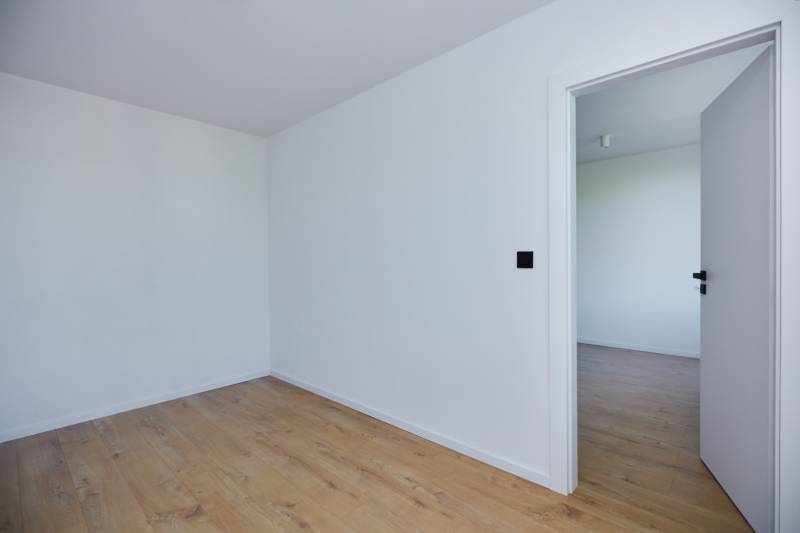 Empty room with wooden floor and open doors in a 2-room apartment.