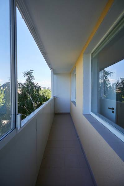 A glazed balcony in a 2-room apartment with a view of greenery.