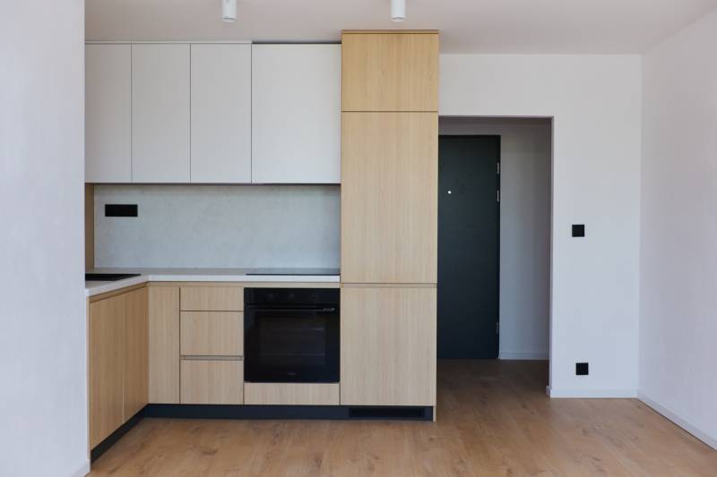 A kitchen in a 2-room apartment with wooden cabinets and black appliances.