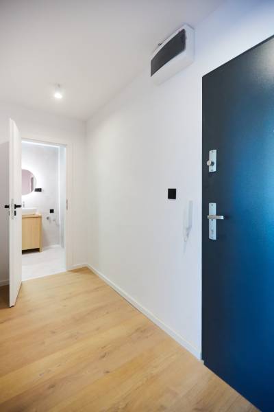 Entrance hall in a 2-room apartment with wooden flooring and a bathroom in the background.